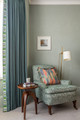 A green upholstered armchair in Ramble by And Objects, paired with a Pop Art Border, brings a quiet rhythm to this space by Otta Design. Natural texture and soft structure invite you to ramble in and rest awhile.